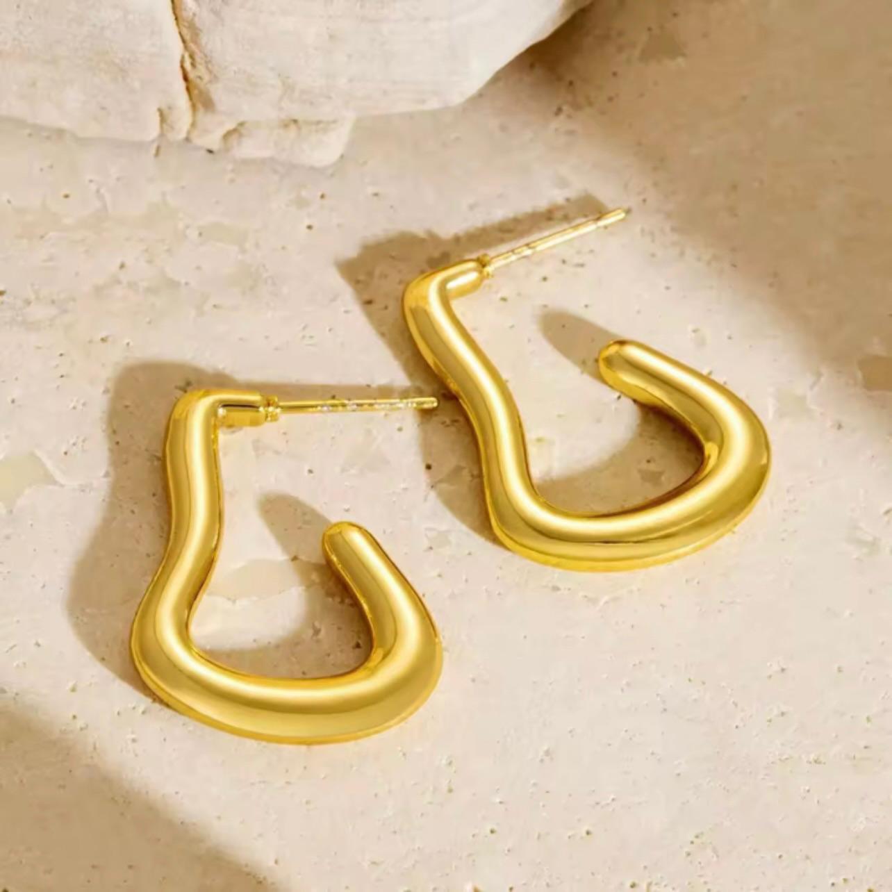 Pair of 18K gold plated abstract-shaped drop earrings on a white surface – waterproof, hypoallergenic, and anti-tarnish.