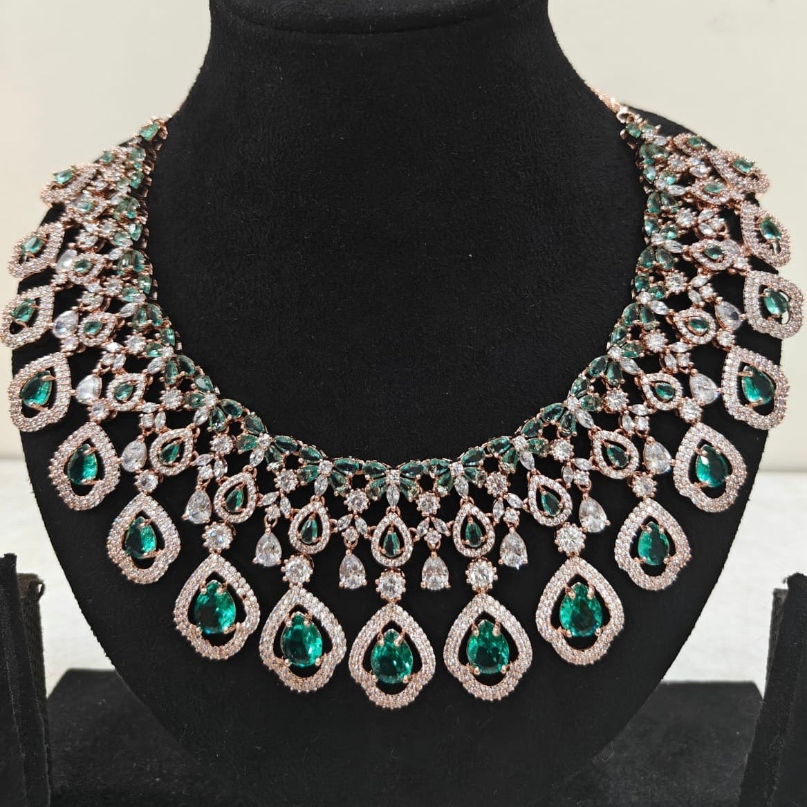 Close-up of rose gold American Diamond necklace with emerald green teardrop stones