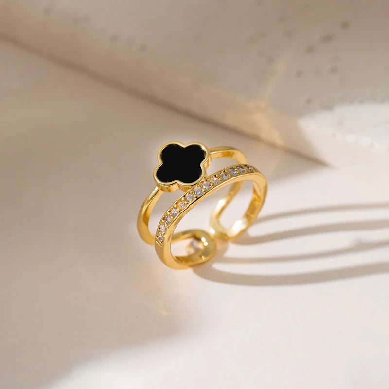 Gold ring with a black clover-shaped center on a light background
