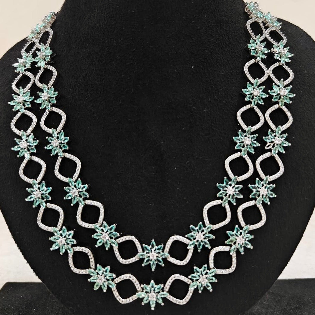 Close-up of emerald green and American Diamond double-layered necklace with starburst design